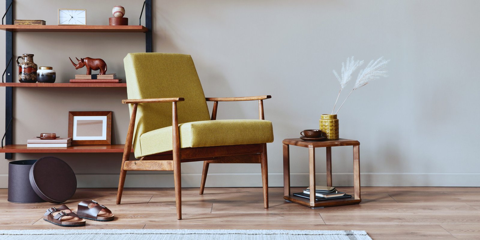 Stylish composition of retro living room interior with design armchair, wooden bookcase, coffee table, picture frames, plant, carpet, slippers, decoration and elegant accessories in home decor. Template.